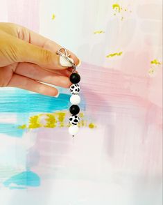 a woman's hand holding onto a beaded necklace with black and white beads