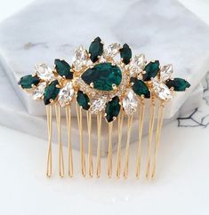 a close up of a hair comb with green and white stones on it's side