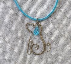 a cat necklace with a blue bead hanging from it's side on a cord