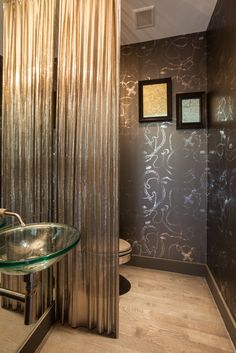 a bathroom with a glass sink and shower curtain in the corner, along with two pictures on the wall