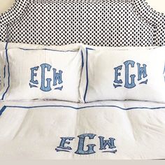 the bed has two pillows with letters on them and blue trimmings around the edges