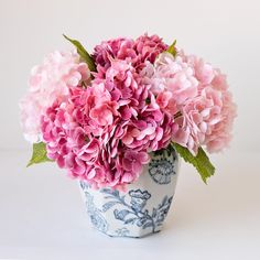 a blue and white vase filled with pink flowers