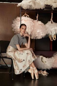 a woman is sitting on a chair in front of some feathers