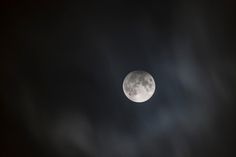 the full moon is seen through dark clouds