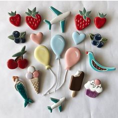 many different shaped cookies are arranged on a white tablecloth with balloons, birds, and other food items