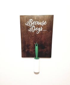 a sign that says because dogs is hanging on the wall with a green toothbrush in it