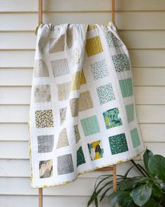 a potted plant sitting next to a quilt hanging from a hook on a wall