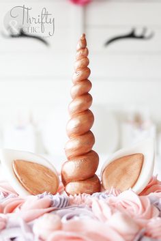 a close up of a cake decorated with pink flowers and wooden unicorn ears on top