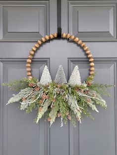 a wreath with pine cones and evergreens is hanging on the front door to welcome guests