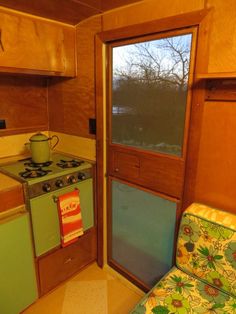 a small kitchen with an oven, stove and chair in it's center room