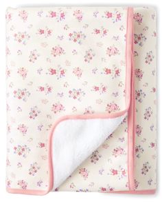 a baby blanket with pink trim and floral print on the bottom, rolled up in half