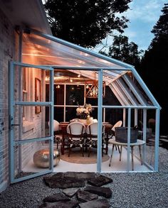 an outdoor dining area is lit up with string lights and glass doors that lead into the backyard