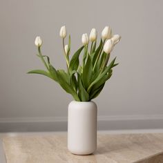 a white vase filled with flowers on top of a table