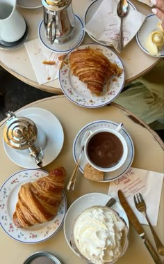 two plates with croissants and ice cream on them sitting on a table