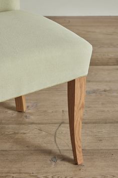 an upholstered chair with wooden legs on a hard wood floor