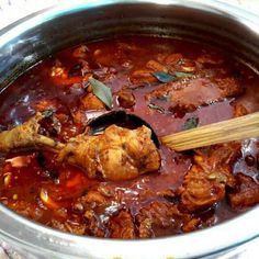 a pot filled with meat and sauce on top of a wooden spoon in the middle of it