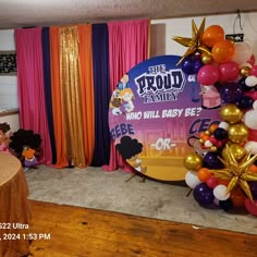 balloons and streamers are set up in front of a backdrop for the proud family who will baby bee's celebration