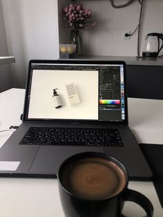 an open laptop computer sitting on top of a desk next to a cup of coffee