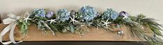 some blue flowers and greenery on a wooden board