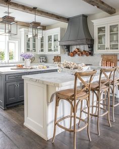 a kitchen with an island, stove and chairs in front of the counter top area