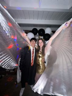 two people posing for a photo in front of some balloons and streamers at a party