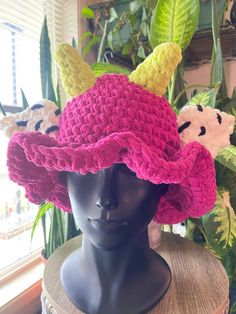 a crocheted pink hat with two stuffed animals on it's brim