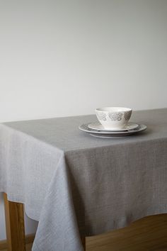 a white bowl sitting on top of a wooden table next to a cup and saucer