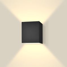 a black square light fixture mounted on the side of a wall in an empty room