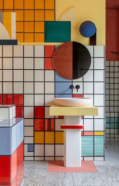 a bathroom with multicolored tiles on the wall and sink in front of it