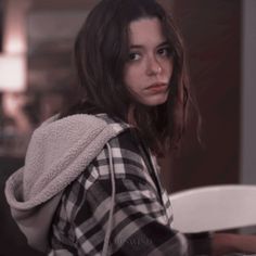 a woman sitting at a table with a plate in her hand and looking off to the side