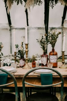 the table is set with wine bottles and candles for an intimate dinner or reception in a greenhouse