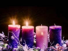 three lit candles sitting next to each other on top of a table covered in snow