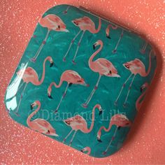 a green tray with pink flamingos on it sitting on a pink wall next to glitter