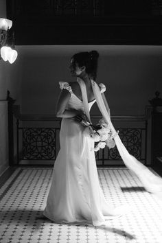 a woman in a long white dress standing on a tiled floor