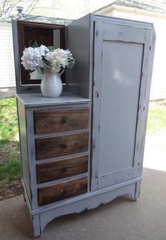 an antique storage chest with flowers on top in front of a white vase and window