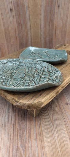 two green ceramic plates sitting on top of a wooden table