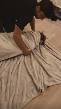 a person bending over on a bed with a blanket