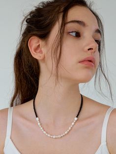 a woman wearing a necklace with pearls on it