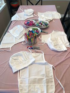 several aprons are laid out on a table with crayons and markers in them