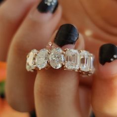 a woman's hand with black and white nail polish holding a ring that has three stones on it