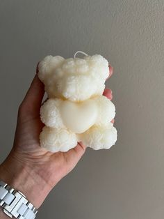 a hand holding a white teddy bear made out of fake flowers and heart shaped soap