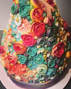 there is a cake decorated with flowers on the top and bottom layer, as well as a hand reaching for it