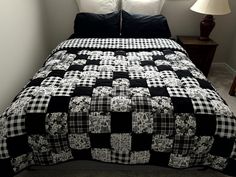 a black and white checkered quilt on a bed with two lamps in the corner