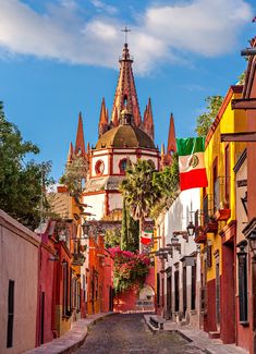 a narrow street with buildings and flags on the top of each building in different colors