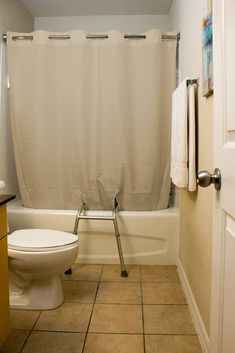 a white toilet sitting next to a bath tub in a bathroom under a shower curtain