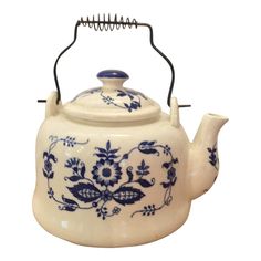 a blue and white teapot with a wire handle on it's side, decorated with flowers