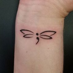 a small dragonfly tattoo on the wrist