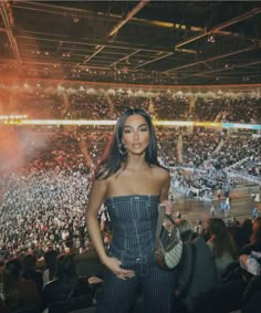 a woman standing in front of a crowd at a basketball game with her hand on her hip