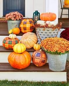 pumpkins, gourds and flowers are sitting on the steps in front of a house