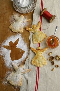 three pastries on a table with powdered sugar and spoons next to them